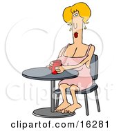 Blond Caucasian Woman In A Pink Dress Sitting Barefoot At A Table And Cupping Her Hands Around A Warm Red Mug Of Coffee