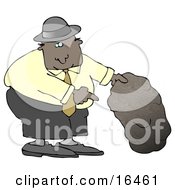 African American Man In A Black Hat Blue Shirt Slacks And Gray Shoes Holding Up A Rock And Pointing Underneath It