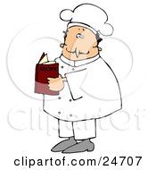 White Male Chef In A White Uniform And Hat Standing And Reading A Recipe Book In A Kitchen