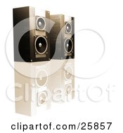 Pair Of Black Stereo Speakers In Brown Lighting Side By Side On A Reflective White Surface