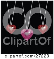 Two Sparkling Red And One Pink Disco-Like Heart Pendants Suspended From Silver Necklaces Over A Black Background