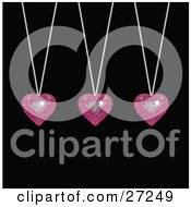 Three Sparkling Pink Disco-Like Heart Pendants Suspended From Silver Necklaces Over A Black Background