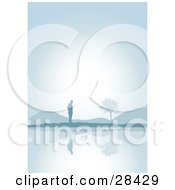 Poster, Art Print Of Lone Silhouetted Man Standing Near Hills And A Tree Reflecting On The Still Waters Of A Lake On A Foggy Morning