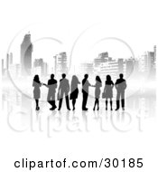 Clipart Illustration Of A Group Of Silhouetted Male And Female Corporate Business People Standing In Front Of A Background Of Gray City Skyscrapers by KJ Pargeter