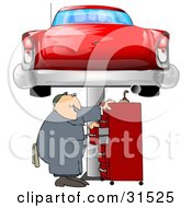 White Male Mechanic Looking For Tools In A Red Tool Box Under A Red Classic Car Up On A Lift In A Garage