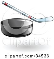 Clipart Illustration Of A Black Hockey Puck Flying Forward A Hockey Stick In The Background by AtStockIllustration