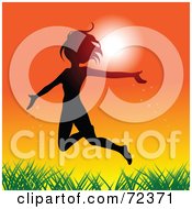Silhouetted Woman Leaping Over Grass Against An Orange Sunset