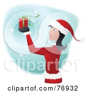 Poster, Art Print Of Woman In A Santa Suit Holding Up A Present In The Snow