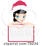 Poster, Art Print Of Black Haired Blue Eyed Christmas Woman Leaning Over A Blank Sign And Wearing A Santa Hat