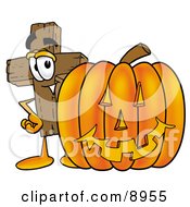 Wooden Cross Mascot Cartoon Character With A Carved Halloween Pumpkin