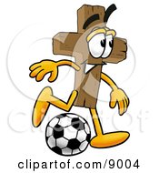 Wooden Cross Mascot Cartoon Character Kicking A Soccer Ball