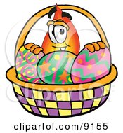 Flame Mascot Cartoon Character In An Easter Basket Full Of Decorated Easter Eggs